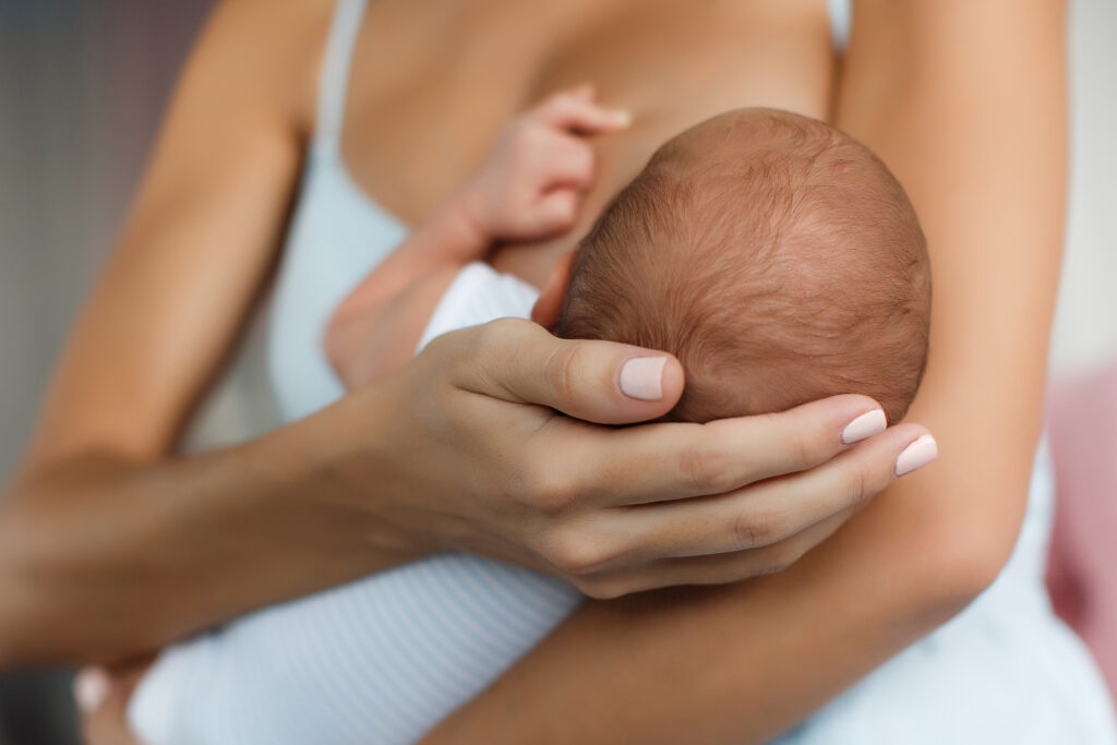 Mutter hält Kopf von Baby während sie es stillt